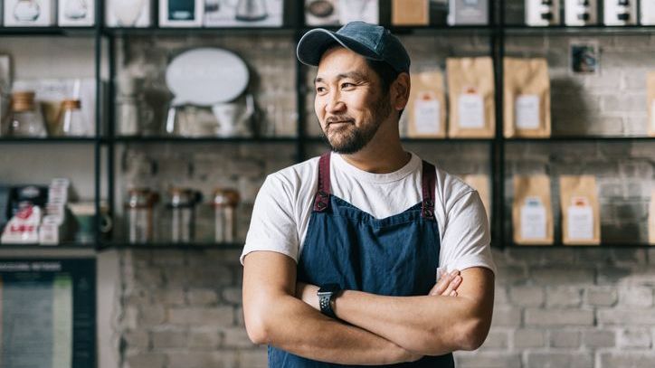 A coffee shop employee stands with his hands crossed during a shift. 