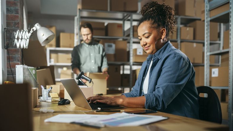 A small business owner looks over her financials while an employee works in the background.