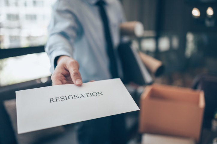 A businessman hands a resignation letter to his boss, symbolizing quitting or leaving a job.